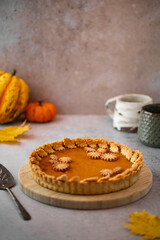 Traditional Pumpkin Pie for Thanksgiving dinner with decorative pumpkins and leaves. Homemade pastry. Holiday dessert.