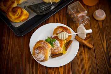 Pastries. Sweet buns with cottage cheese filling and honey in a plate on a wooden table