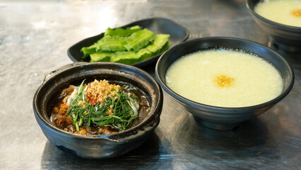 Eminent frog porridge or Singapore frog porridge and green onion in clay pot. Singapore braised frog and spring onion. Spicy frog porridge. 