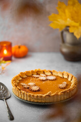 Traditional Pumpkin Pie for Thanksgiving dinner with decorative pumpkins and leaves. Homemade pastry. Holiday dessert.