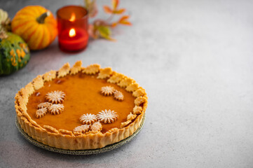 Traditional Pumpkin Pie for Thanksgiving dinner with decorative pumpkins and leaves. Homemade pastry. Holiday dessert.