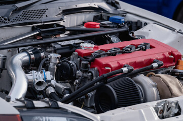 Fototapeta premium The engine of a car is shown in detail, with the hood open to reveal the inner workings. The engine is red and white, and it is a high-performance vehicle. Concept of power and speed
