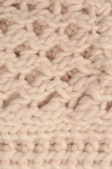 A fragment of beige knitted fabric, knitted from white sheep wool.