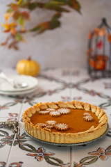 Traditional Pumpkin Pie for Thanksgiving dinner with decorative pumpkins and leaves. Homemade pastry. Holiday dessert. American cuisine