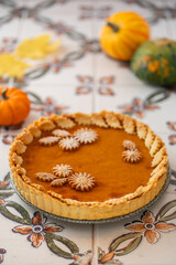 Traditional Pumpkin Pie for Thanksgiving dinner with decorative pumpkins and leaves. Homemade pastry. Holiday dessert. American cuisine