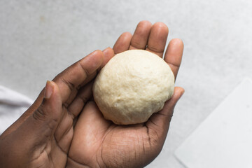Overhead view of challah dough being shaped in hand, top view of homemade challah bread dough, process of making challah