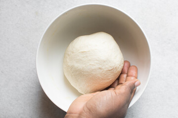 Overhead view of challah dough being shaped in white bowl, top view of homemade challah bread dough, process of making challah