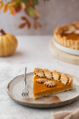 Traditional Pumpkin Pie 
for Thanksgiving dinner with decorative pumpkins and leaves. Homemade pastry. Holiday dessert for single serving. A piece of Pumpkin Pie.