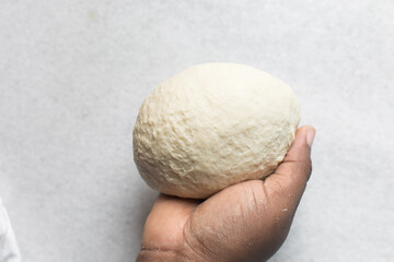 Overhead view of challah dough being shaped in hand, top view of homemade challah bread dough, process of making challah