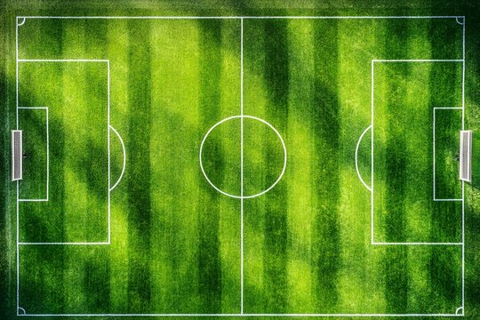 Aerial view of an empty soccer field, vibrant green grass, white lines, and goals. - Powered by Adobe
