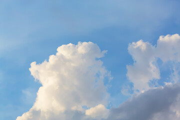 Fluffy white clouds float in a bright blue sky, creating a peaceful and serene scene, ideal for...