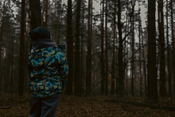 Fototapeta premium A lost child calls for help in a dark autumn forest, representing the spirit of exploration despite fear and danger. A child lost in the forest looks into the darkening forest.