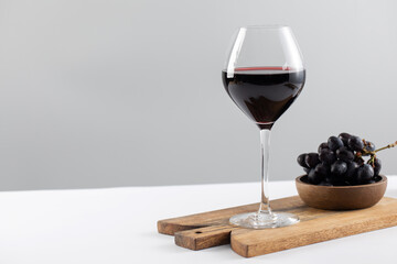 Red wine glass and black grapes served on wooden board. Copy space