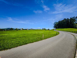 Tranquil Rural Scene with Curving Road and Feather Clouds