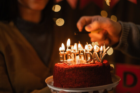 Woman holding birthday cake man lighting candles happy birthday inscription on cream cake, party concept