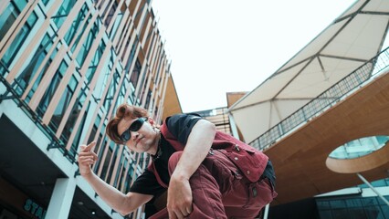 Low angle of asian attractive hipster pose at camera surround by mall. Portrait of break dance...