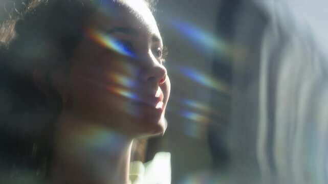 Close-up face of teenage girl, bathed in soft light, gazing upwards with serene expression, rainbow-like streaks illuminating her features against blurred background