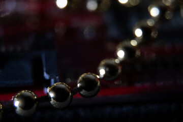 Christmas macro of metallic spheres on a red circuit board. Reflective surfaces and a blurred background evoke technological sophistication and New Year aesthetics.