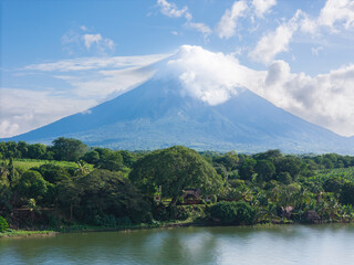 Obraz premium Green lake shore with blue sky and volcano