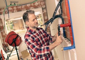 Handyman (plumber) tightens a valve on a water pipes - domestic water installation.