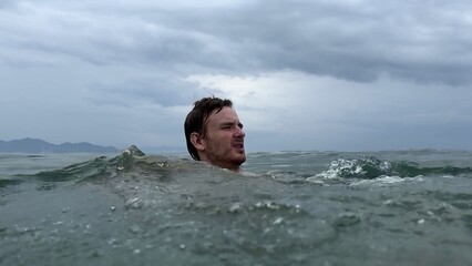 Young scared frightened man having panic attack, drown in water, phobia in the sea