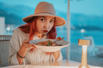Woman disgusted by her spaghetti while dining in restaurant by the sea