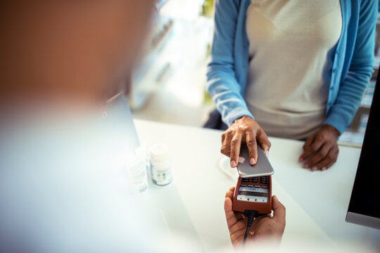 Woman making contactless smartphone payment at pharmacy
