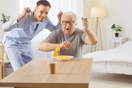 Happy caregiver playing a ball game with an senior man patient, spending leisure time together at a nursing home. Engagement and activity, offering fun and companionship in a care setting.