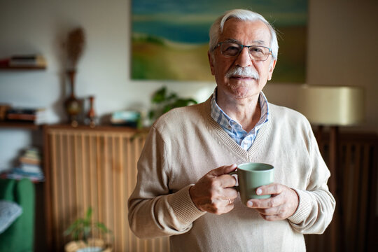 Senior man looking out window holding coffee mug