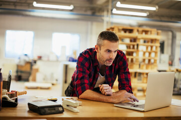 Young man using a laptop while working in a printing press office