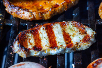 Marinated pork steak and chicken steak on the grill grate with flames