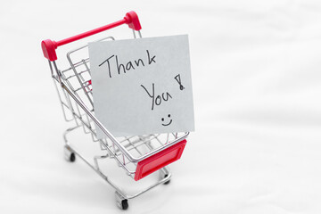 Thank you note affixed to shopping cart retail store marketing content indoor close-up business...