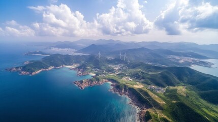 Breathtaking Aerial View of a Coastal Landscape Featuring Rolling Hills, Clear Waters, Wind Turbines, and Scenic Mountains Under a Bright Blue Sky with Fluffy Clouds.