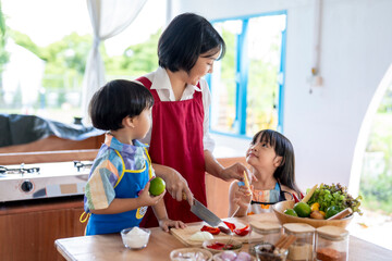 Asian family cooking together in kitchen cutting vegetables