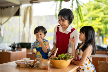 Happy asian family preparing ingredients for cooking together in kitchen