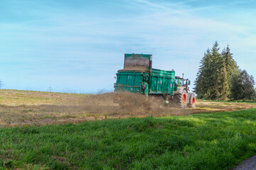 Shredder drives across a field and throws chaff into a trailer