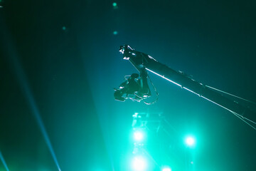 Video cameras on a crane with green beam spot and light on a rock concert stage as background, Studio lighting with cameras, equipment film on set.
