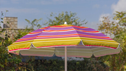 One Colourful Open Parasol in Yard at Sunny Autumn Day