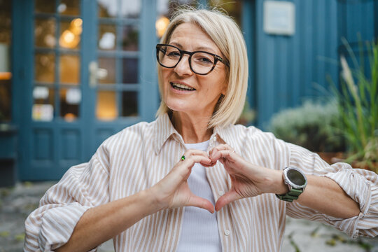 portrait of mature woman sit connect fingers show heart symbol - Powered by Adobe