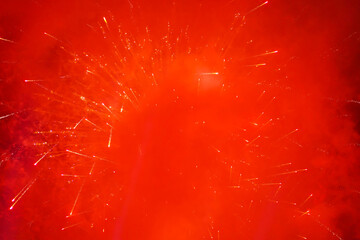 Red and orange sparks lights of fireworks in the dark sky and smoke from the charges for Silvester,...