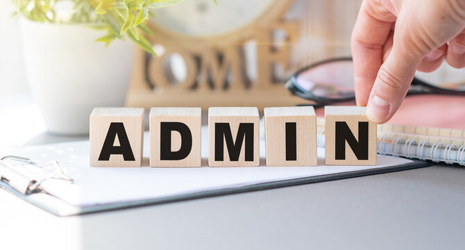 ADMIN inscription on the texture of wooden cubes. A business woman holds a cube in his hand. An inscription on a financial, business or economic theme.