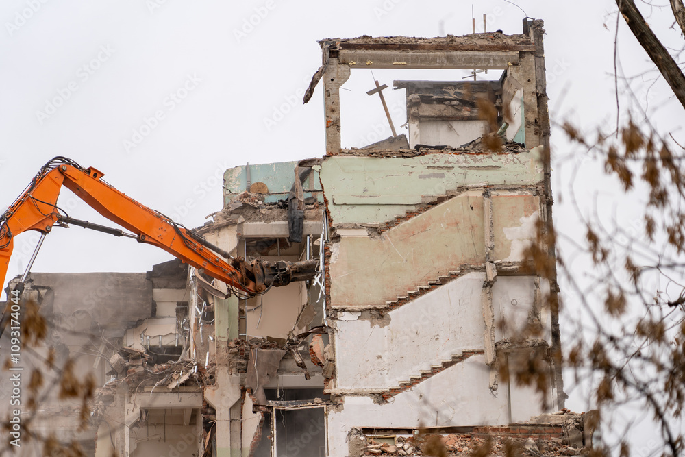 Poster heavy machinery is tearing down a dilapidated building under overcast skies, marking an end to its s