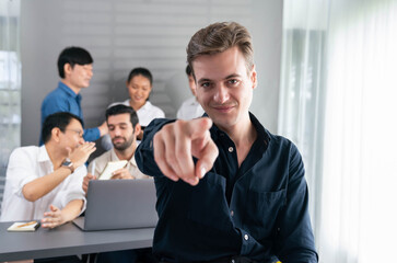 Obraz premium Confidence and happy smiling businessman portrait with background of his colleague and business team working in office. Office worker teamwork and positive workplace concept. Prudent