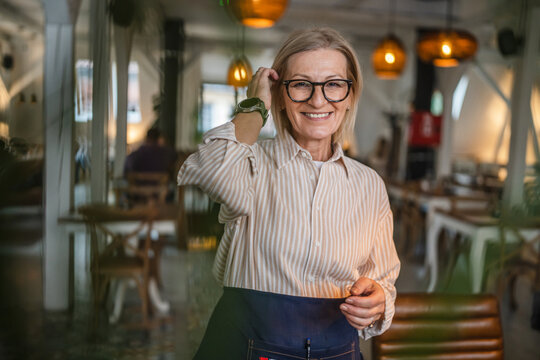 Portrait of a happy spontaneous mature woman stand at restaurant