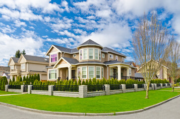 Fototapeta premium Neighbourhood of luxury houses in summer with street road, big trees and nice landscape in Vancouver, Canada. Blue sky. Day time on August 2024.