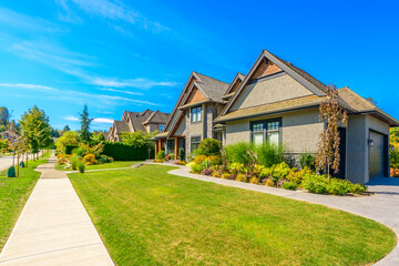 Neighbourhood of luxury houses in summer with street road, big trees and nice landscape in Vancouver, Canada. Blue sky. Day time on August 2024.