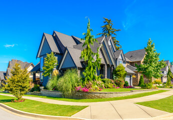 Neighbourhood of luxury houses in summer with street road, big trees and nice landscape in Vancouver, Canada. Blue sky. Day time on August 2024.
