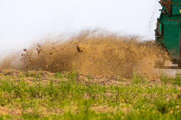 Shredder drives across a field and throws chaff into a trailer
