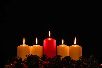 four white advent candles in a row that are lit, with a red lit Christ candle in the center, and...
