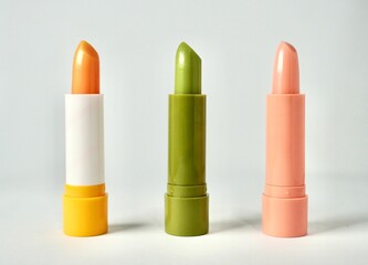 Three orange, green, and pink tinted lip balm cosmetic care product set isolated on horizontal...
